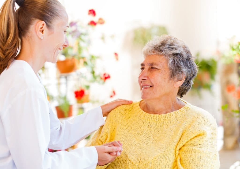 Accompagnante posant la main sur l'épaule d'une femme âgée, sourires complices